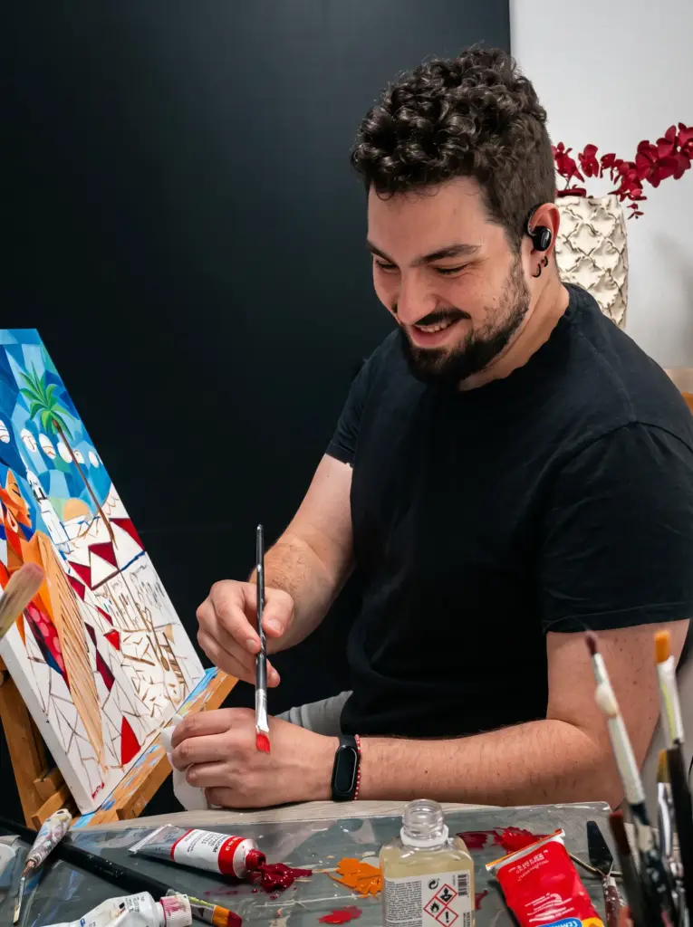 Artista sonriente pintando con pincel fino un cuadro colorido